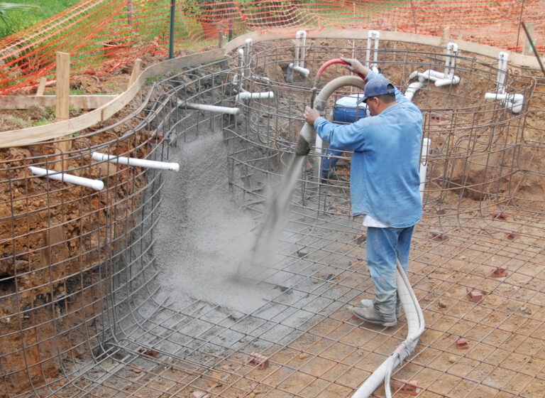 Ein Handwerker spritzt Beton für den Poolbau ein.