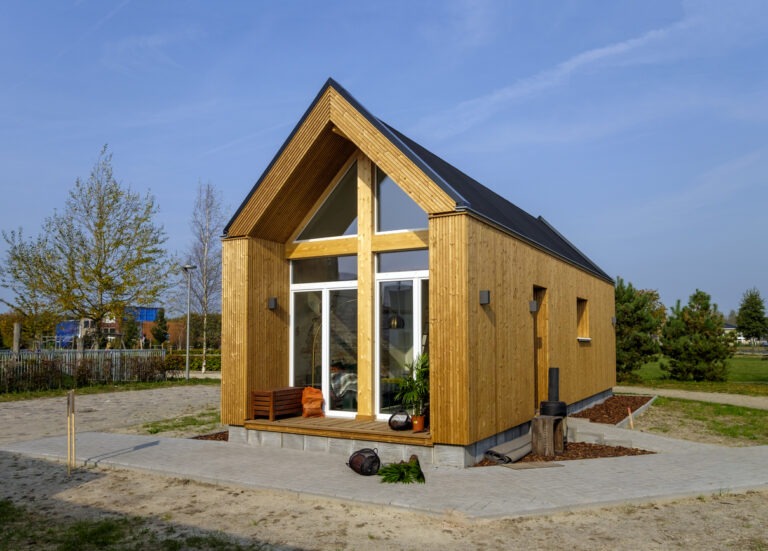 Ein Tiny House mitten in einer schönen Landschaft auf einem hübsch angelegten Grundstück.