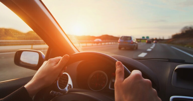 Ein Mann hält beide Hände am Steuer seines Autos und fährt auf der Autobahn.