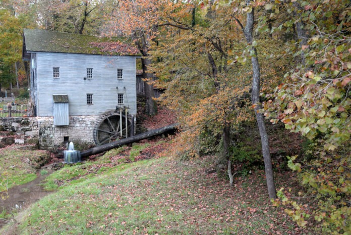 Eine alte Talmühle befindet sich in herbstlicher Umgebung.