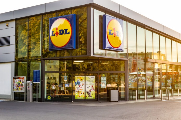 Eine Filiale von Lidl mit der typischen großen Glasfassade und dem Logo im Sonnenschein.