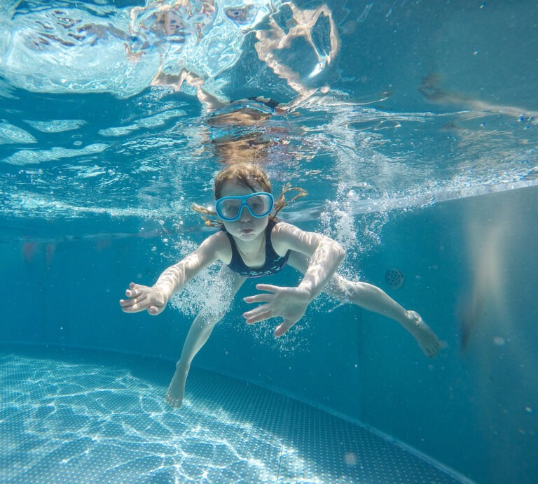 Ein Kind schwimmt in einem Pool unter Wasser.