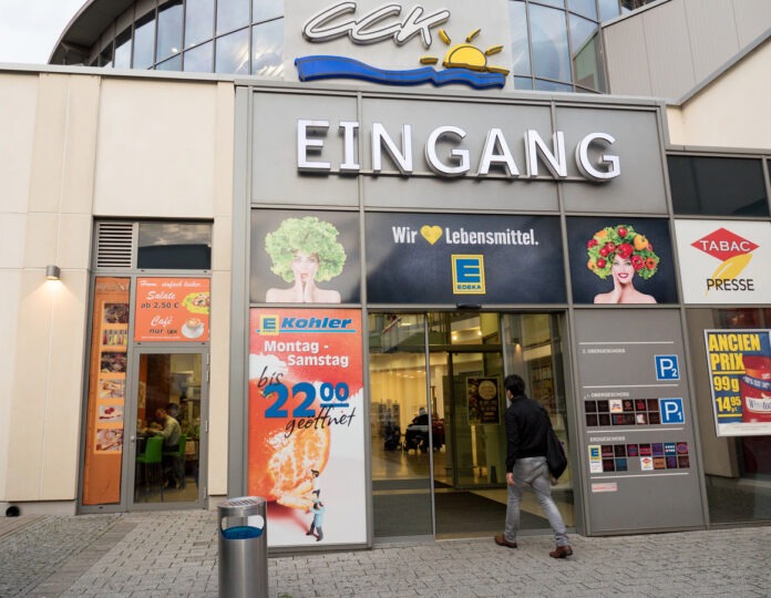 Ein Kunde geht auf den Eingang vom Supermarkt Edeka zu.