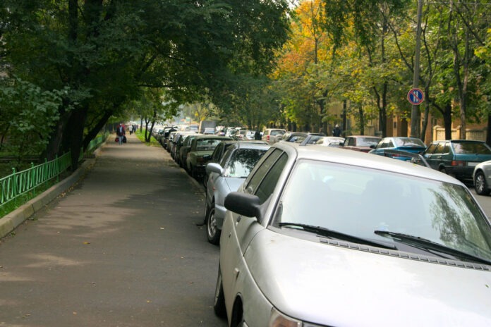 Einige Fahrzeuge parken auf dem Gewheg in einer Siedlung.