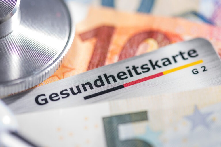 Auf Euro-Scheinen liegt ein Stetoskop und eine Gesundheitskarte einer Krankenkasse.