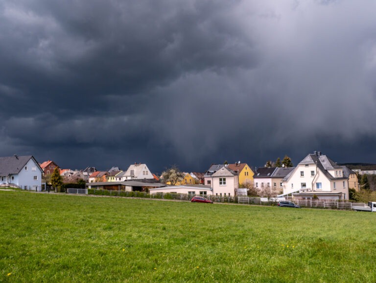 Ein Gewitter zieht über einer Siedlung hinweg.