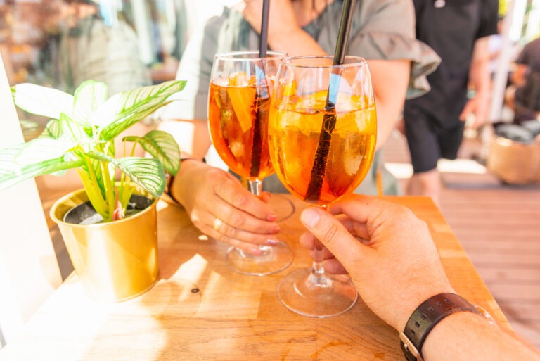 Zwei Gäste stoßen mit Aperol Spritz in einem Restaurant an.