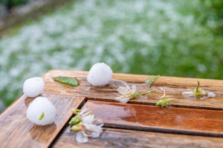 Hagel liegt auf dem Rasen und einige Körner auf dem Tisch.