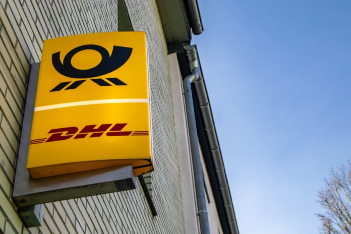 Die Symbole der Deutschen Post und DHL auf einem Schild an einer Hausfassade.