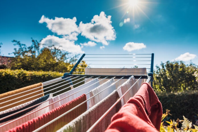 Ein Wäscheständer voller Wäsche steht in der Sonne im Sommer draußen zum Trocknen.