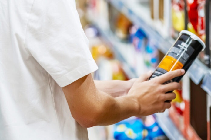 Ein Mann nimmt ein Produkt aus dem Regal im Supermarkt oder Discounter.
