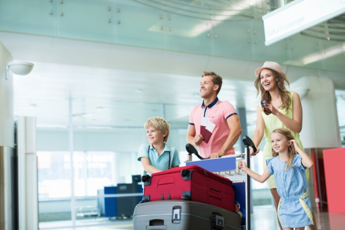 Eine junge Familie ist mit ihrem Gepäck am Flughafen auf dem Weg in den Urlaub.