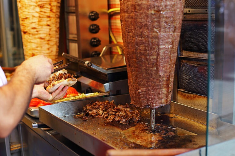 Ein Mann bereitet einen Döner Kebab am Spieß vor.