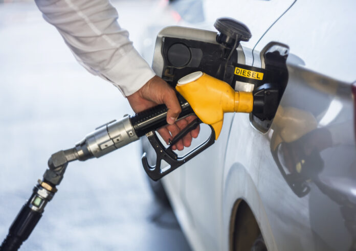 Ein Mann im weißen Hemd tankt an der Tankstelle sein Auto.