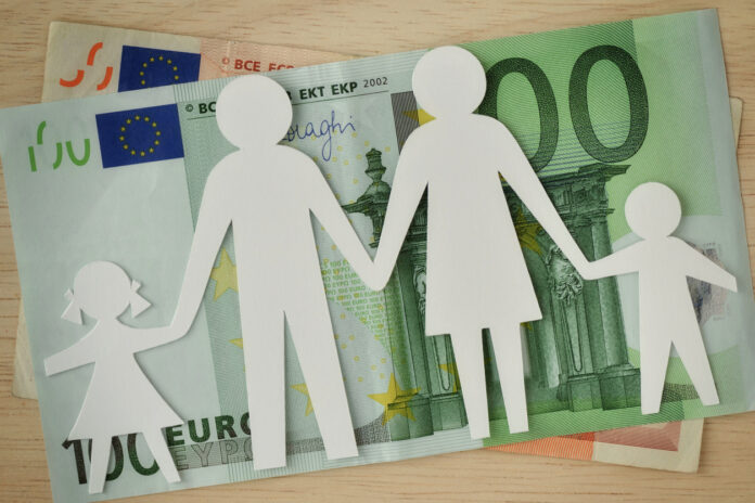 Eine Papierfamilie liegt auf Euro-Scheinen und deutet das Kindergeld an.