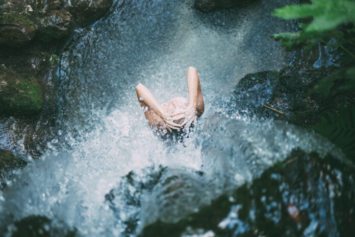 Eine Frau duscht tagsüber in einem Wasserfall